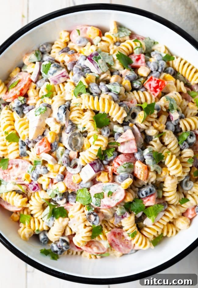 A top down shot of Creamy Southwest Pasta Salad in a white serving bowl, showcasing colorful ingredients.