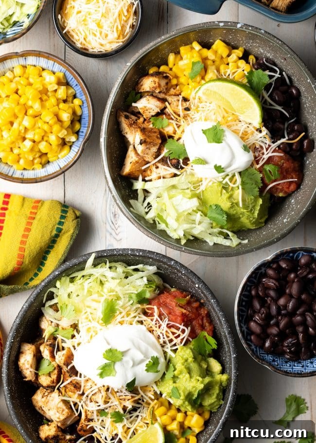 A vibrant photo of several grilled chipotle chicken burrito bowls, topped with black beans, corn, fresh salsa, and other Southwestern garnishes.