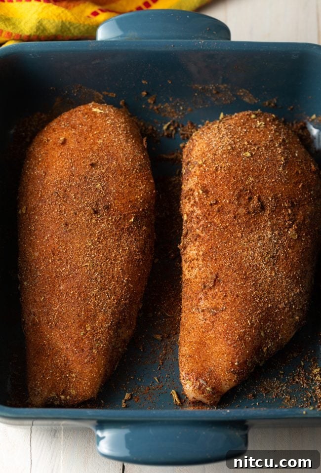 Chicken breasts fully coated with the smoky chipotle seasoning rub in a baking dish.
