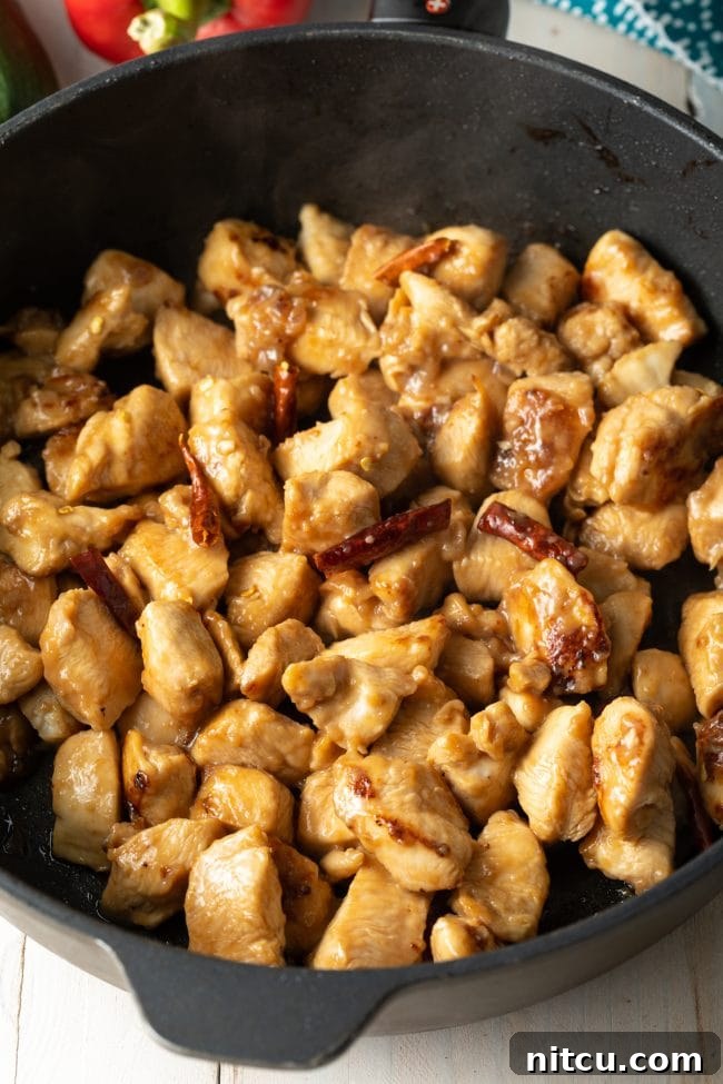 Chopped chicken and red chiles sautéing in a cast iron skillet.