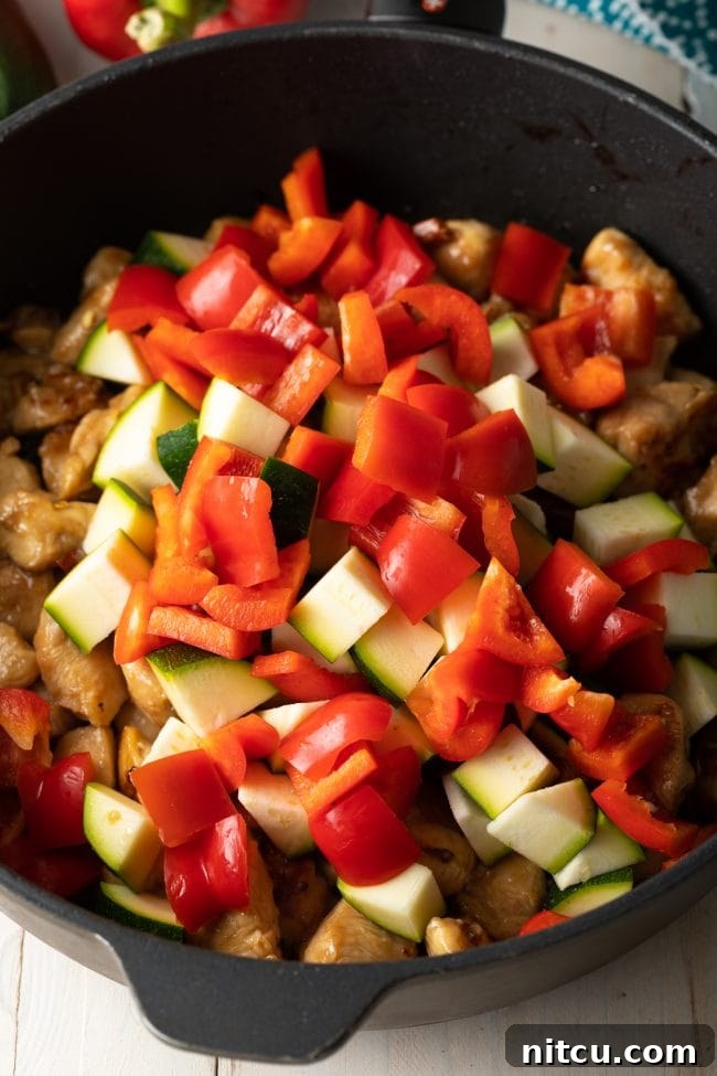 Cast iron skippet with chopped zucchini and red bell peppers.