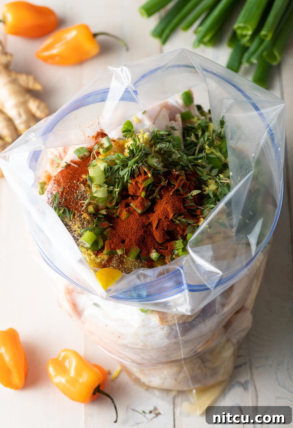 Zip loc bag filled with ingredients for marinade and pieces of raw chicken.
