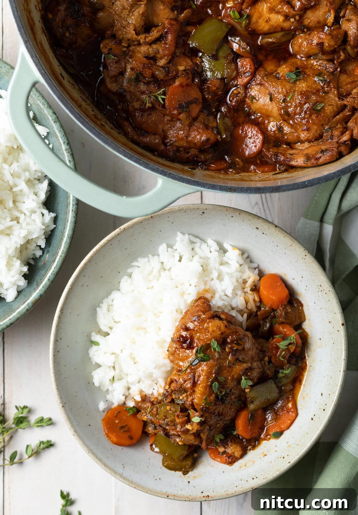 Top down view of plated brown stew chicken recipe with some rice.