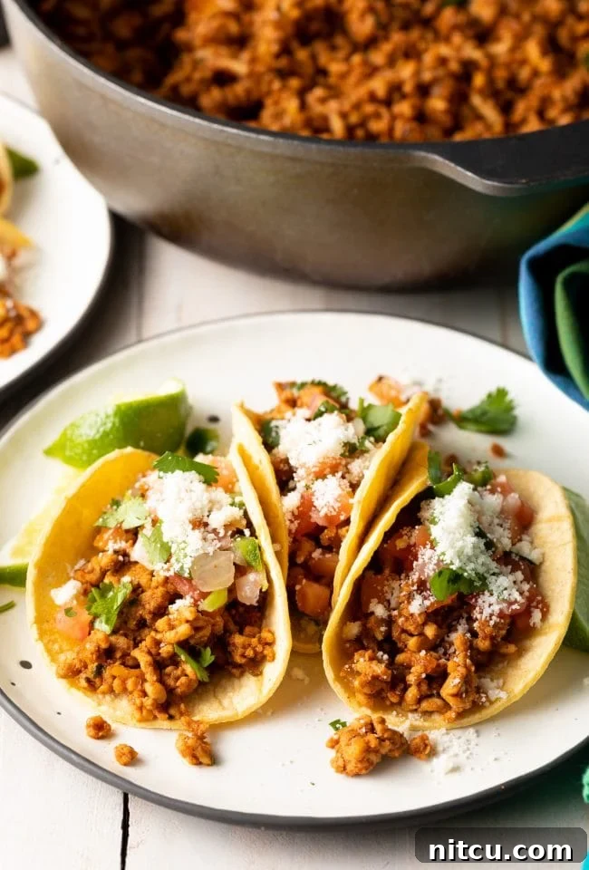 Spicy ground turkey tacos on a plate with a skillet in the background