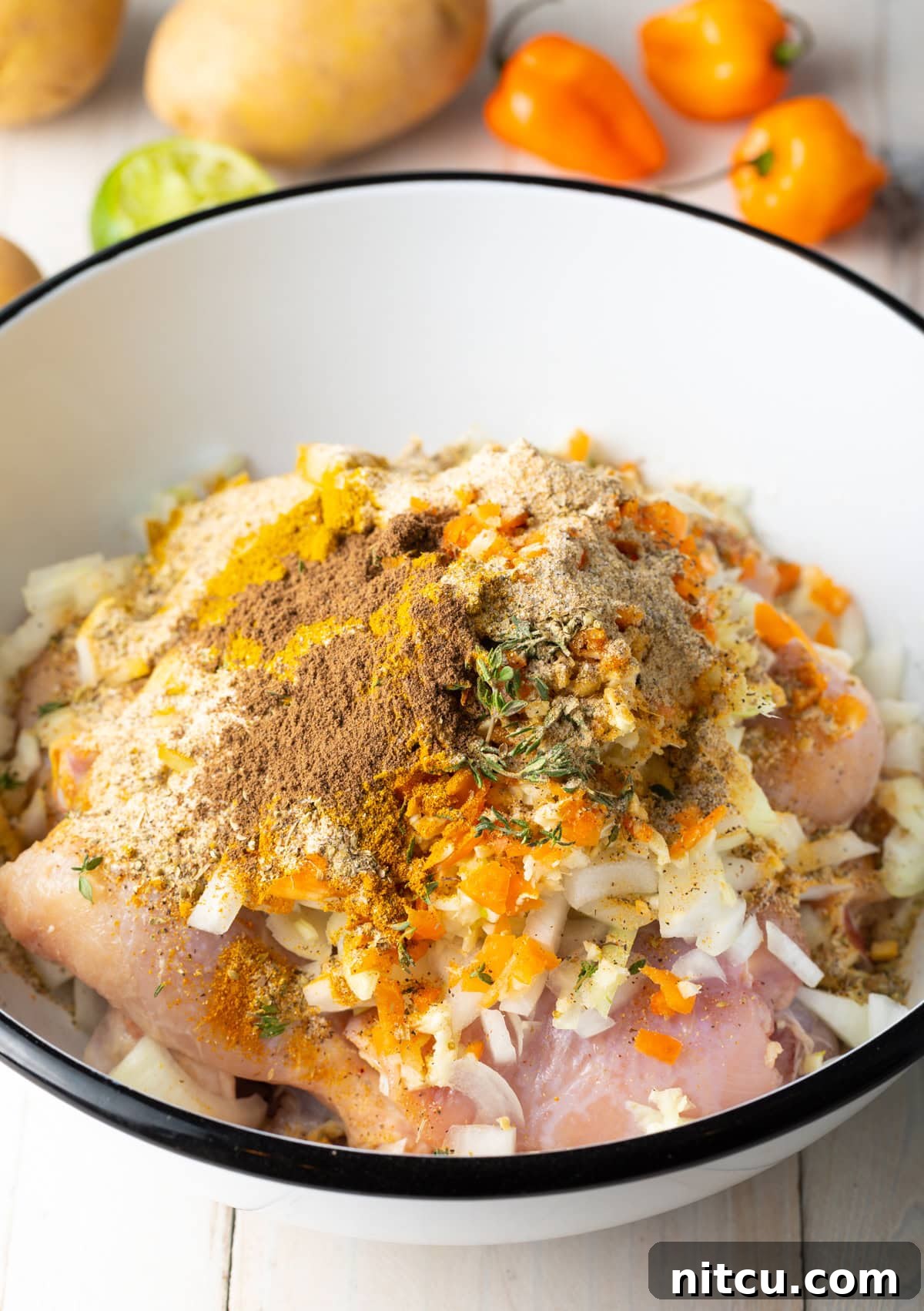 Chicken marinating in a bowl with spices and herbs.