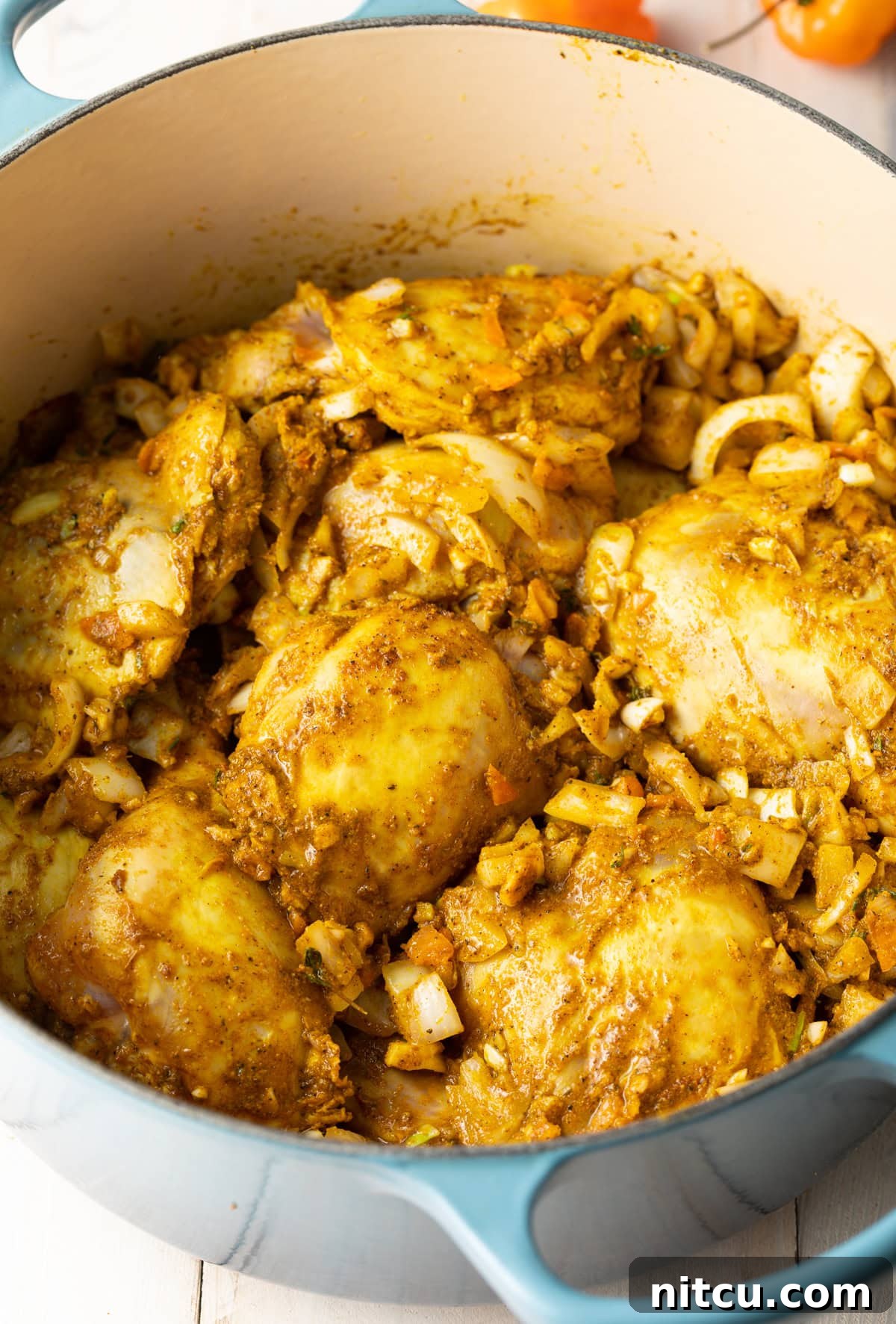 Chicken pieces being browned in a large pot on the stovetop.