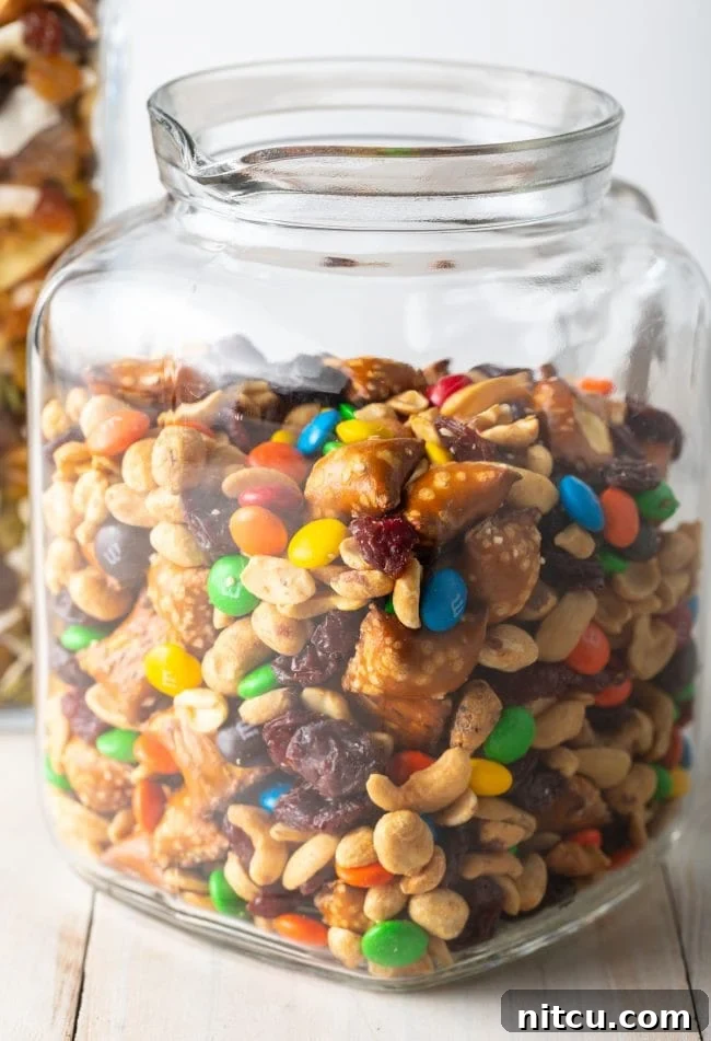 A side view of a glass jar generously filled with indulgent trail mix, showcasing its vibrant contents.