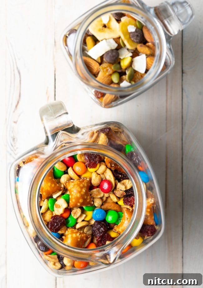 Overhead view of homemade trail mix beautifully arranged in clear glass jars, highlighting various ingredients.