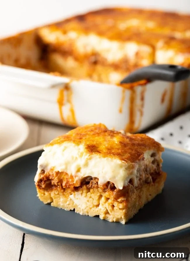 Greek pastitsio square with meat sauce and bechamel, on a gray plate.