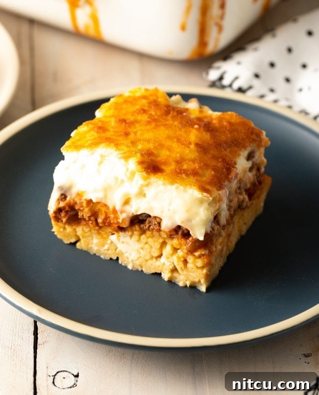 Square of homemade pastitsio on a gray plate.