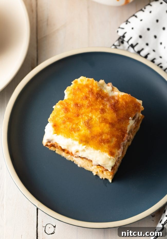 Top down view square of pastitsio on a gray plate.