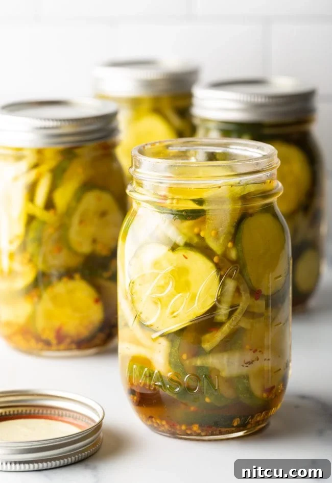 Opened jar of bread and butter pickles with more jars in the background.