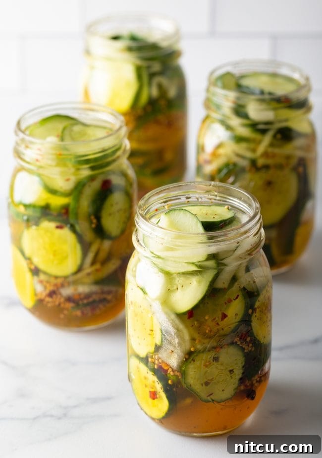 Four jars of cucumbers and onions with pickling liquid.