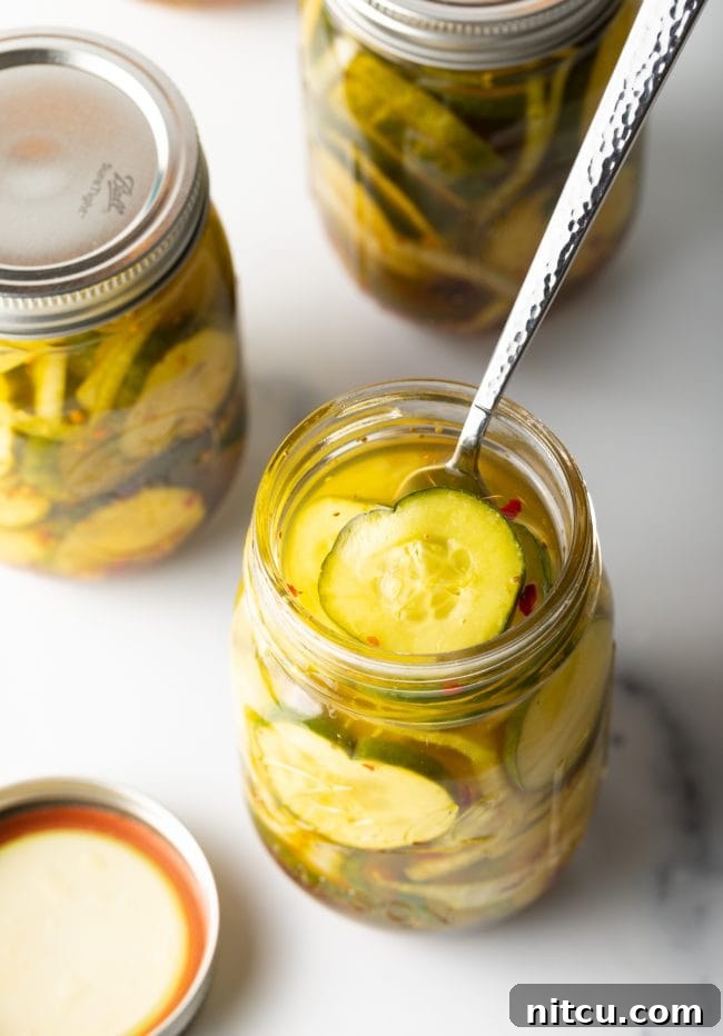 Overhead view of an opened jar of bread and butter sweet pickles with a fork.