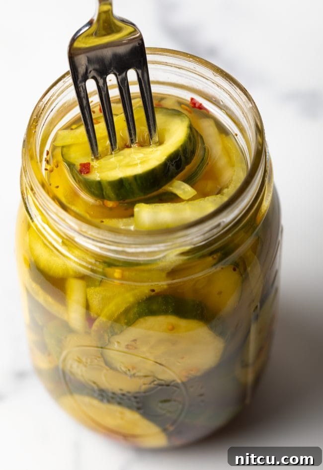 Using a fork to get a sweet pickle slice from a jar.