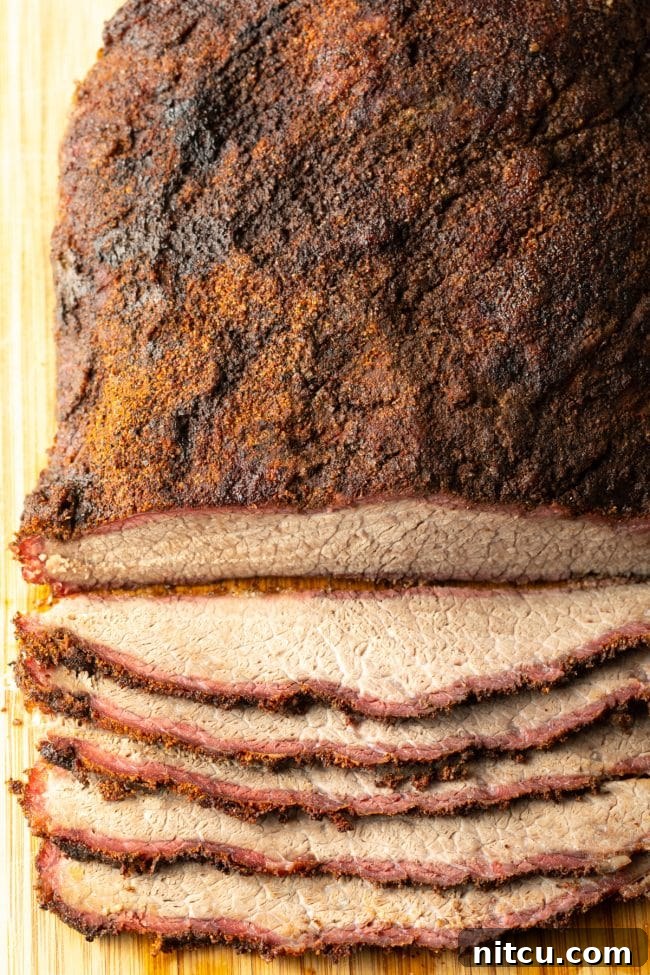 Perfectly smoked beef brisket resting on a wooden cutting board, with several slices already carved.