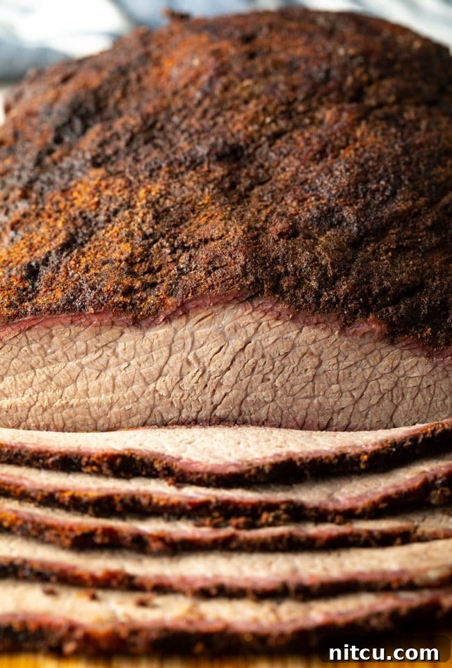 Close-up view of perfectly sliced Texas smoked beef brisket, showcasing its tender texture and smoke ring.