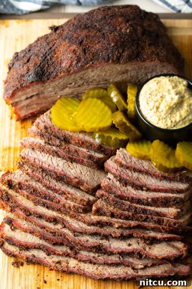 Smoked brisket sliced to perfection, served with pickles and mustard on a wooden board.
