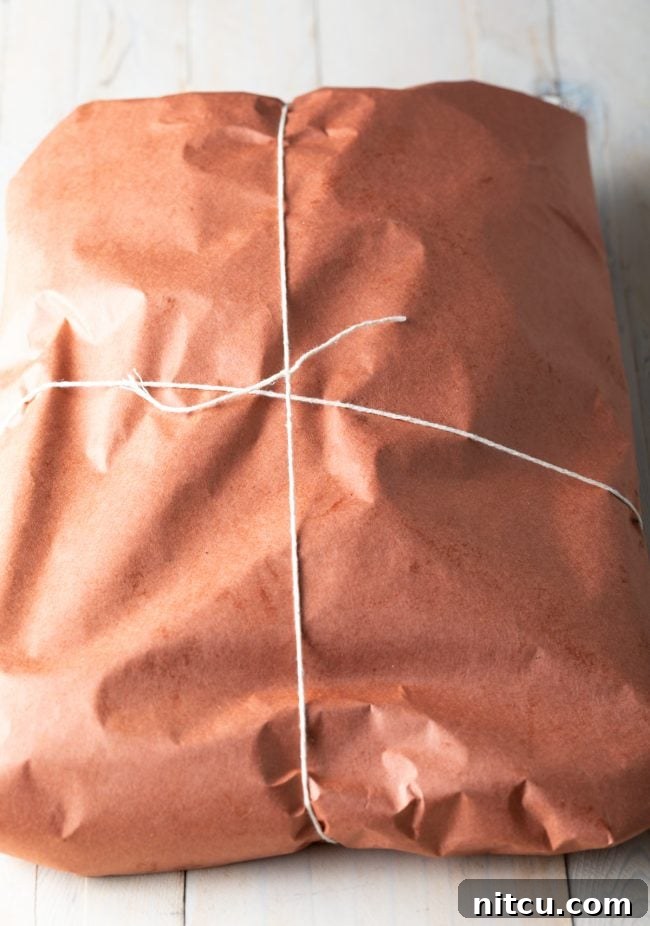 Brisket tightly wrapped in pink butcher paper and secured with kitchen twine.