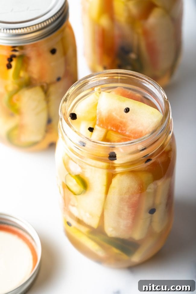 open jar of watermelon pickles with peppercorns