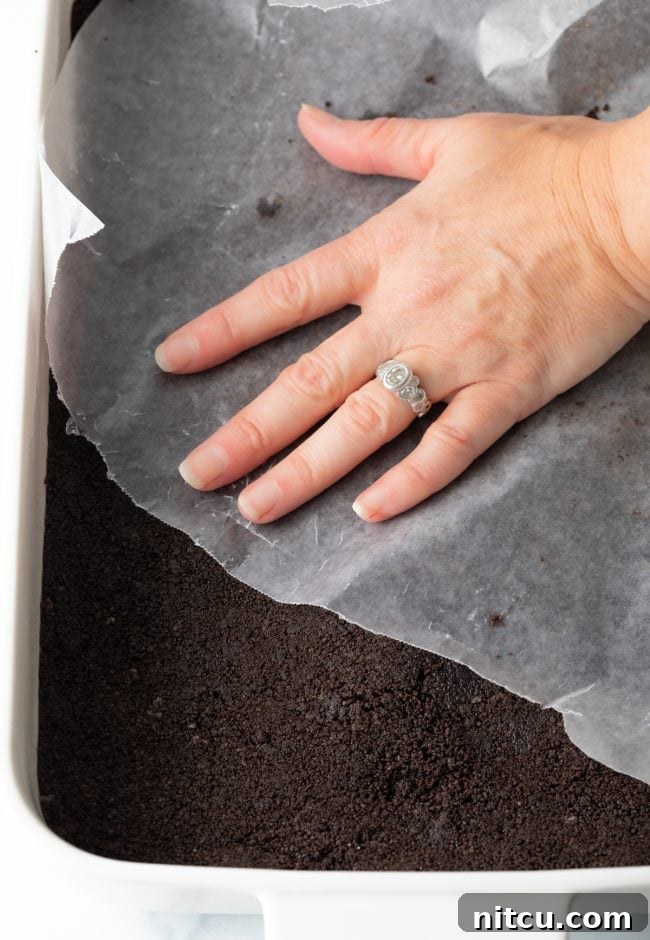 Pressing the Oreo crust into a baking dish.