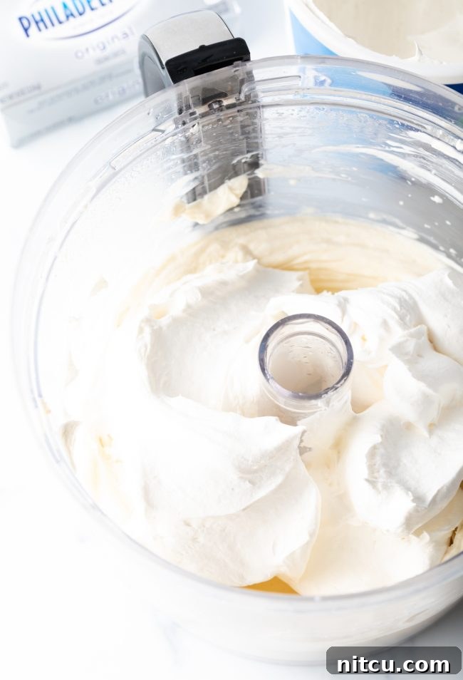 Mixing cream cheese, sugar, and milk in a food processor for the cream cheese layer.