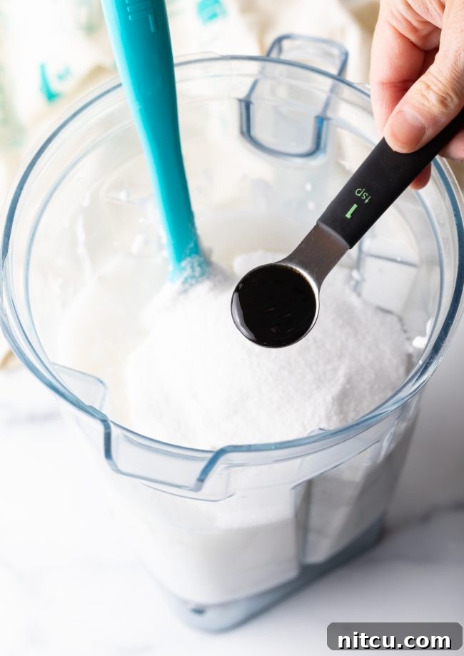 adding vanilla to the blender with coconut milk in it.