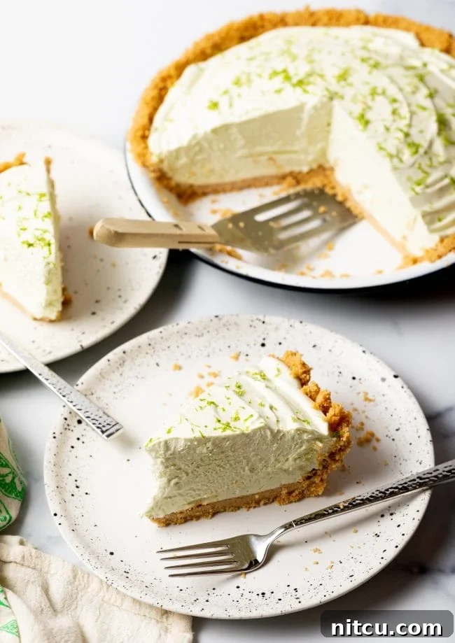 Multiple slices of chilled frozen key lime pie arranged on individual plates in the foreground, with the full, uncut pie visible in the background, creating an enticing display of this refreshing dessert.