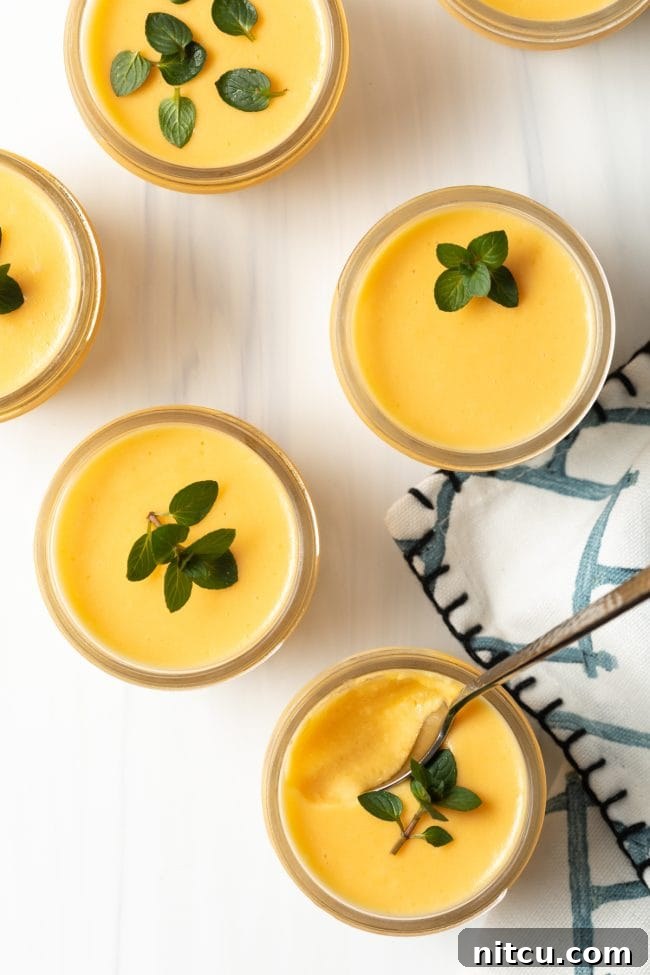 Overhead view of 4 dairy free Chinese mango pudding dessert pudding cups with mint leaves.