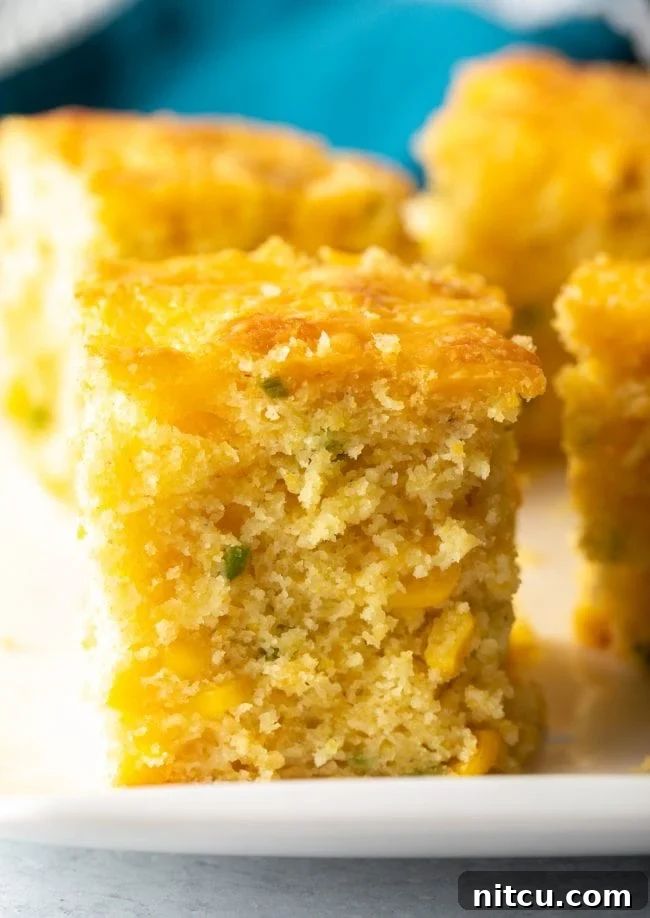 Close-up slice of fluffy jalapeno cheddar cornbread, showcasing its moist texture and cheesy interior.