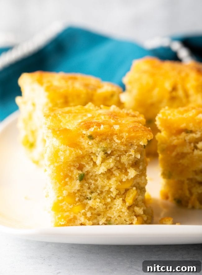 Perfectly cut squares of homemade cheesy cornbread with visible chopped peppers, ready to be served.