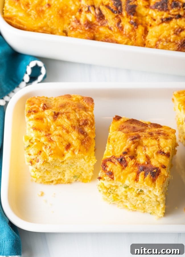 Overhead view of perfectly baked squares of jalapeno cheddar cornbread arranged on a white platter.