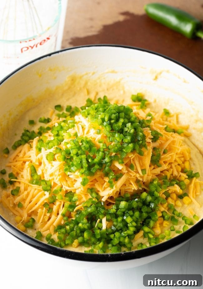 Folding sweet corn, shredded cheddar cheese, and diced jalapenos into the cornbread batter.