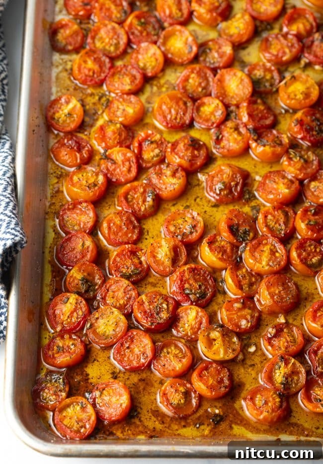 Overhead view of cherry tomatoes roasting in a pan, bubbling with juices and balsamic glaze.