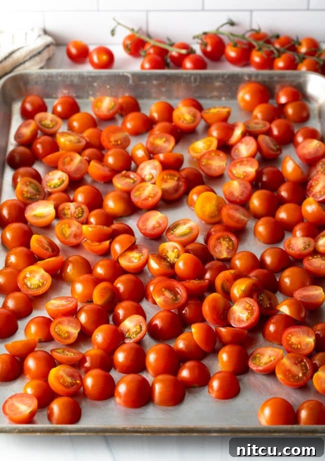 Fresh halved cherry tomatoes arranged on a baking sheet.