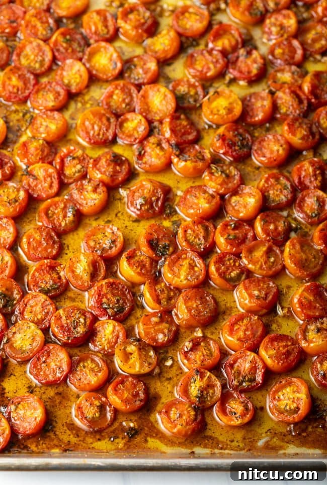 Overhead view of a baking sheet filled with beautifully roasted balsamic cherry tomatoes.