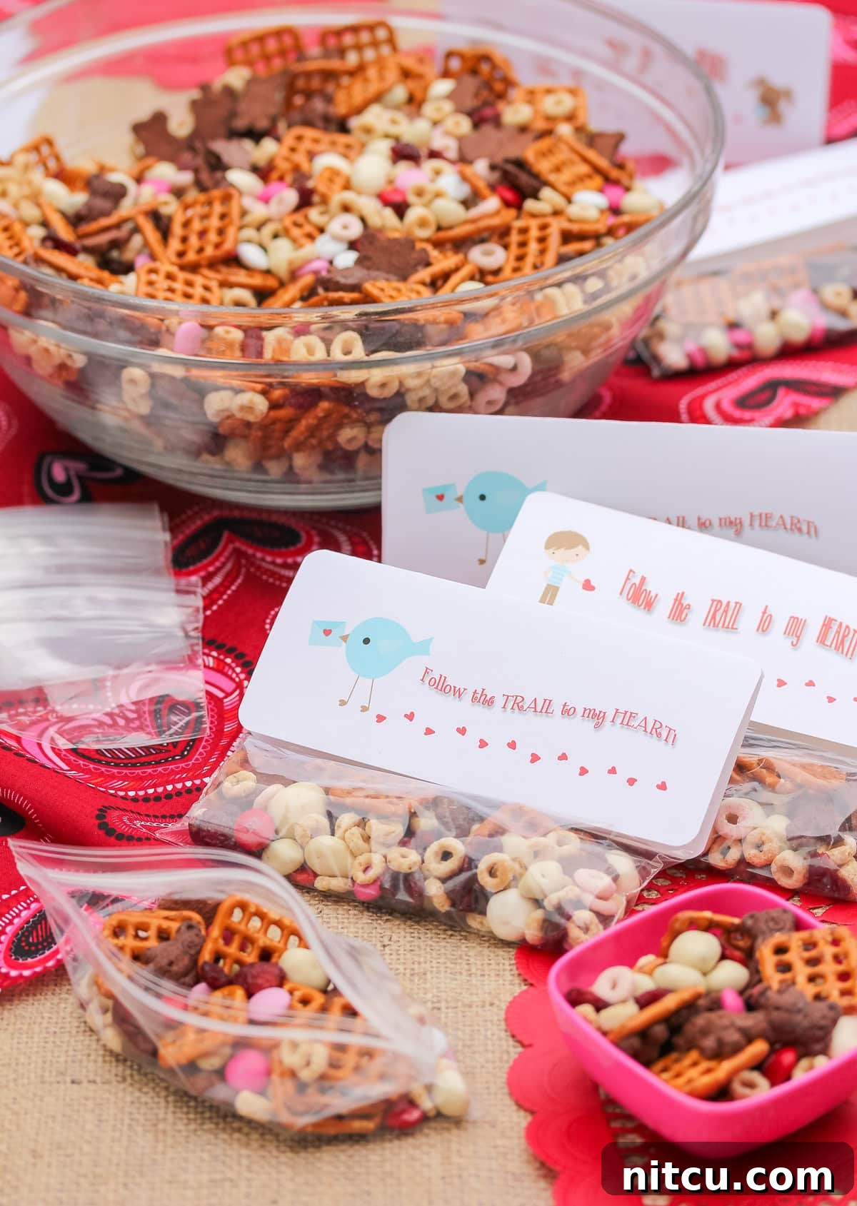 valentines day snacks (trail mix) in individual baggies with a bowl of trail mix in the background.