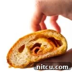 A freshly baked pepperoni roll, sliced open to show the melted cheese and pepperoni inside, resting on a white platter.