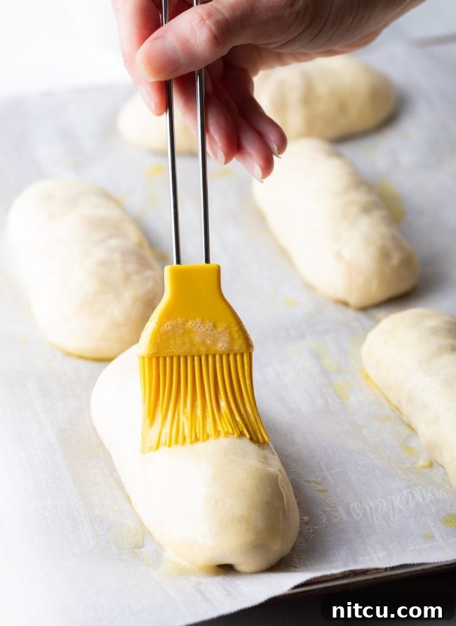Brushing pepperoni rolls with butter.