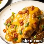 Close-up of a serving of smothered chicken with gravy and cheese.