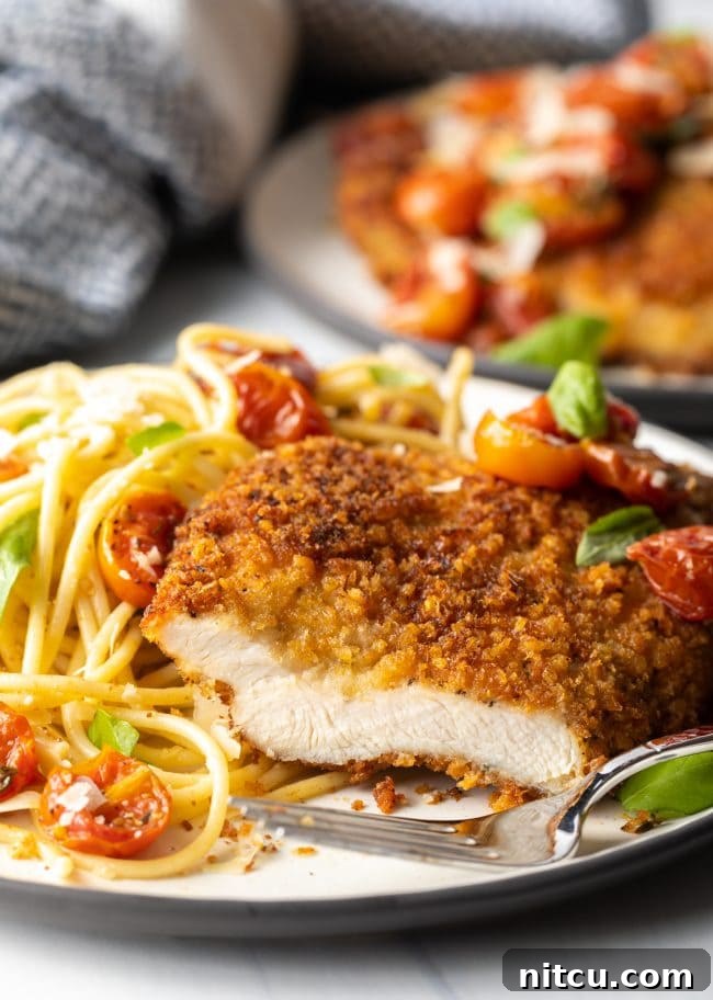 cut breast showing meat inside, on a plate with fork and pasta