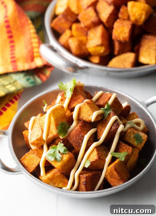 Bowl of crunchy Patatas Bravas topped with aioli and fresh cilantro