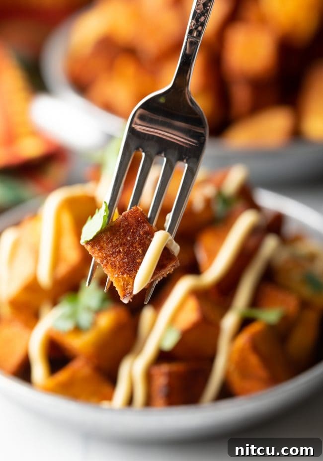 Fork holding a single crispy Mexican fried potato with a hint of sauce and cilantro
