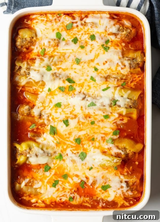 Close-up, top-down view of baked banana peppers in a rich marinara sauce, generously covered with melted cheese and fresh parsley garnish