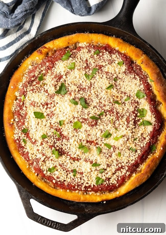 A beautiful top view of a baked Chicago-style pizza, freshly garnished with grated Parmesan cheese and vibrant green parsley, ready to be served.