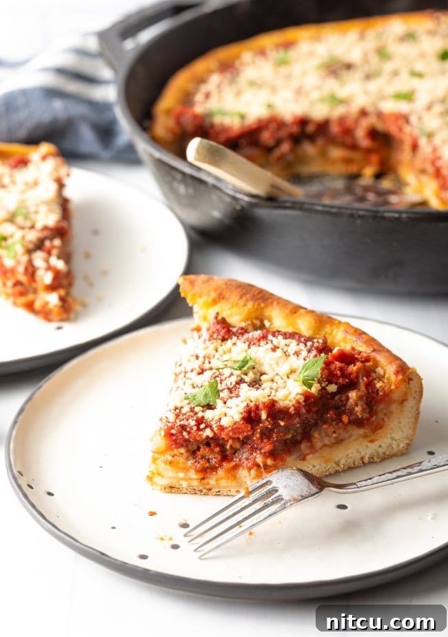 A delicious slice of tomato pie with a fork on a plate, a bite already taken, showing the gooey cheese and rich tomato sauce within the thick crust.
