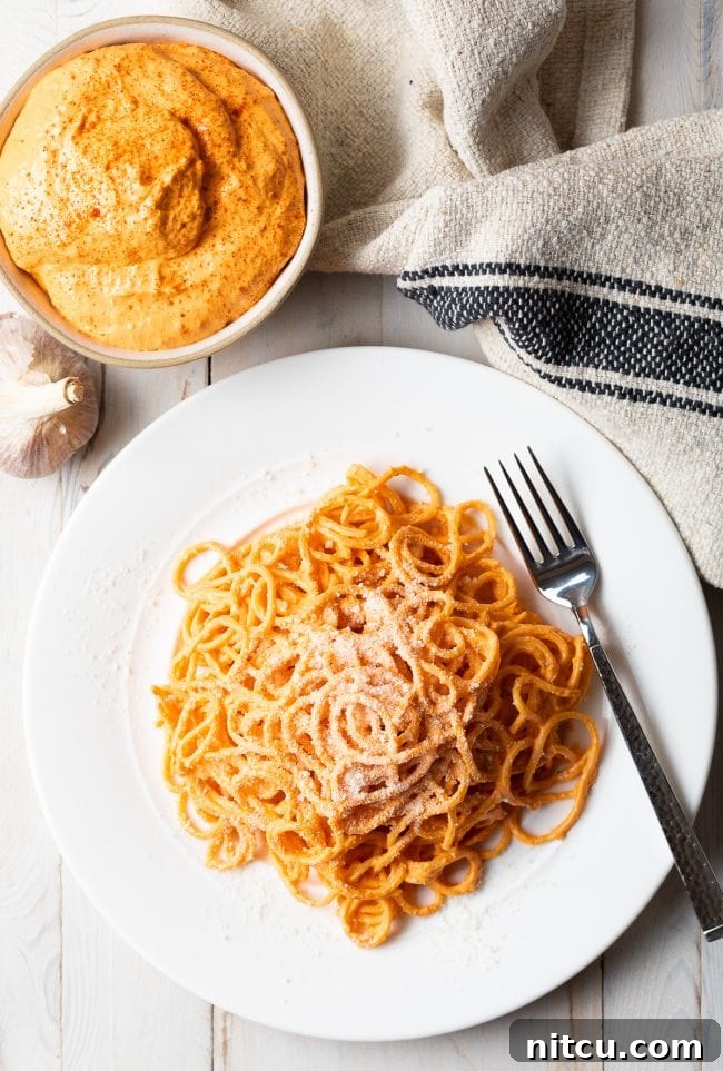 Roasted Red Pepper Sauce served on spaghetti on a white plate. 
