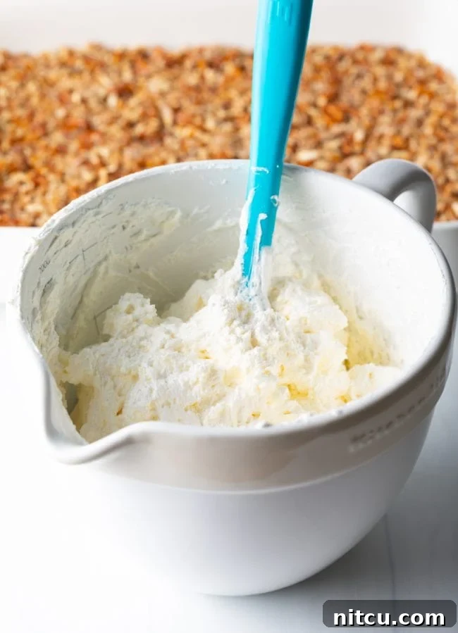 A bowl filled with fluffy cream cheese and cool whip mixture, ready for layering.
