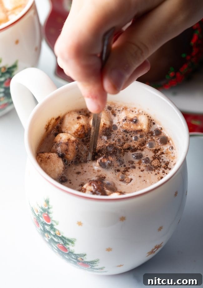 Hand mixing melted chocolate in mug.