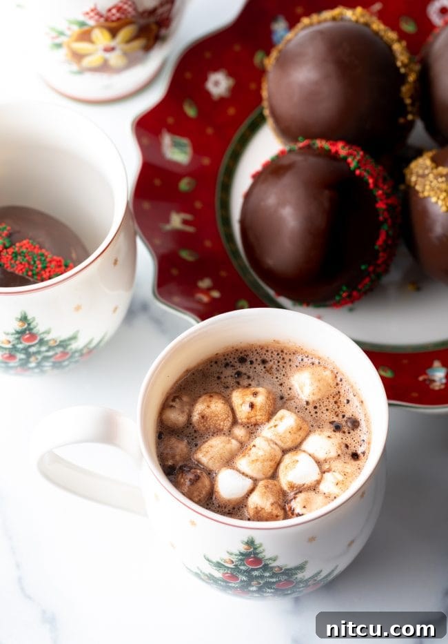 Top down view mug of hot chocolate with marshmallows - chocolate balls in the background.